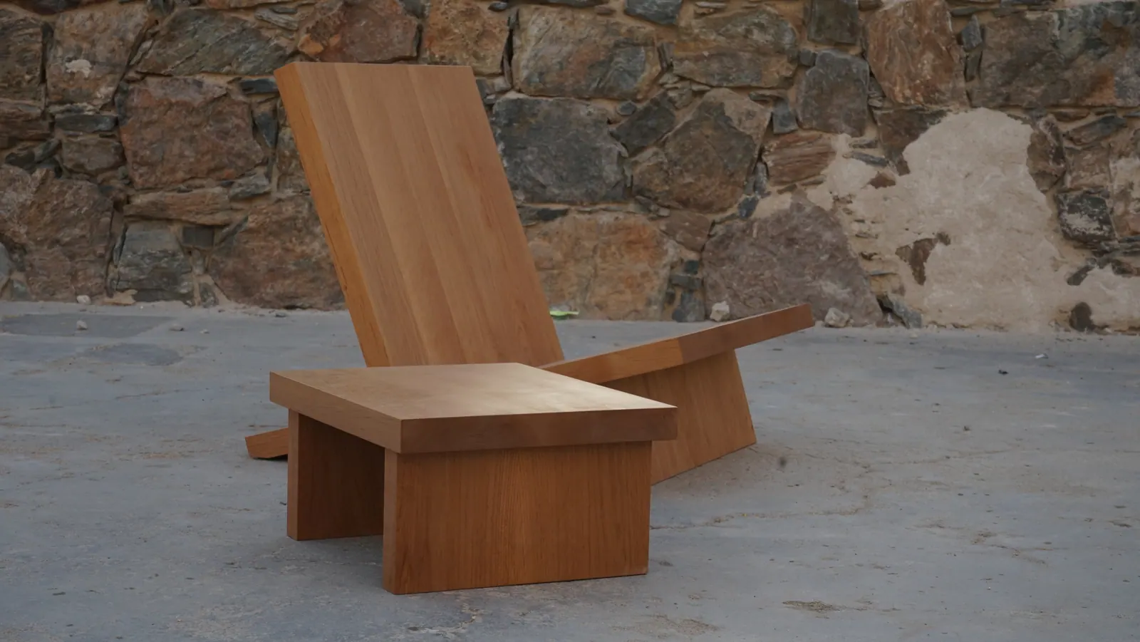 Low wood lounge chair and footstool against a stone wall