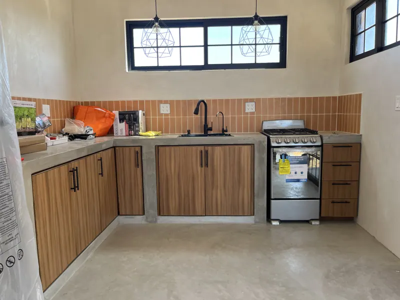 L-shaped kitchen with wood doors set in concrete counters