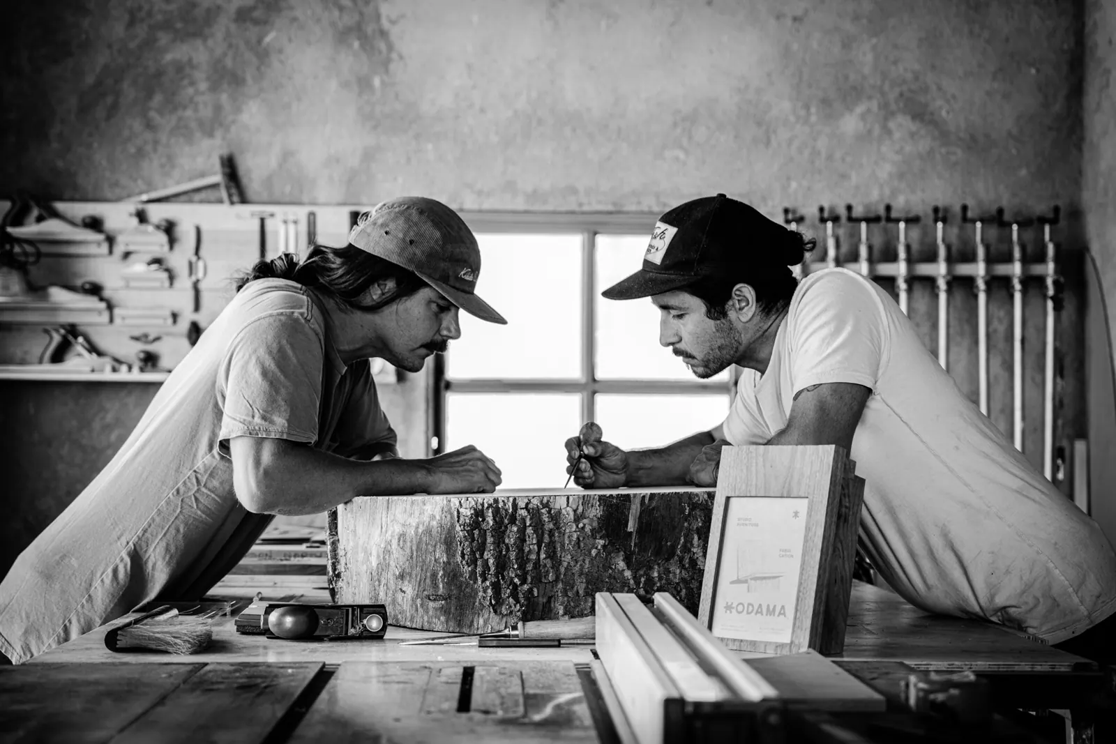 Two woodworkers planning a piece at the workbench